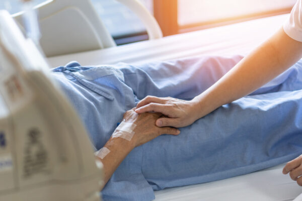Fotografi av helsepersonell med hånd over hånden til døende pasient