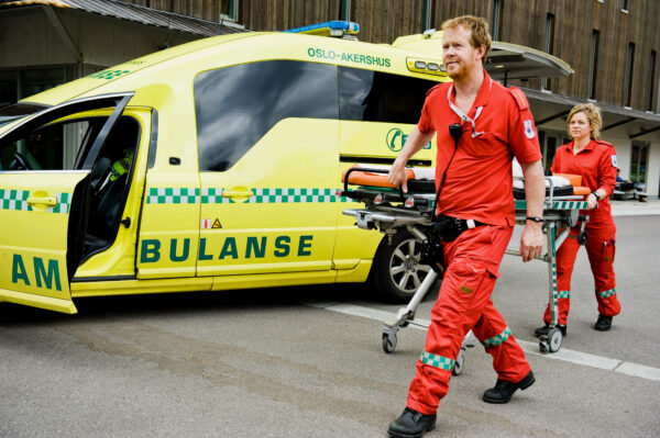 Fotografi av ambulansepersonell foran ambulanse-kjøretøy