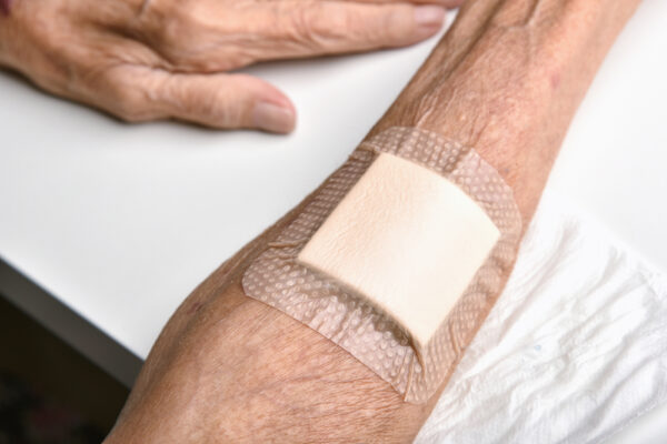 Fotografi av armen til en eldre person, påført plaster