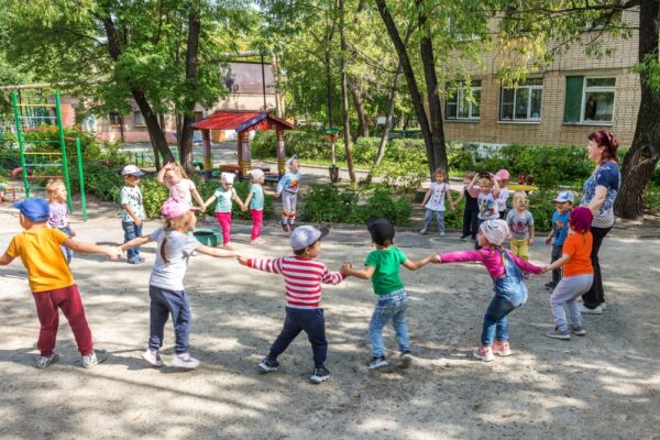 Fotografi av barn på en lekeplass som holder hverandre i hendene og leker