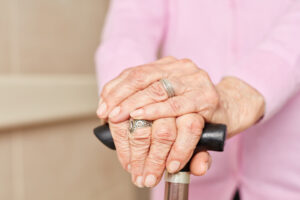 En eldre dame holder hendene sine på en stokk