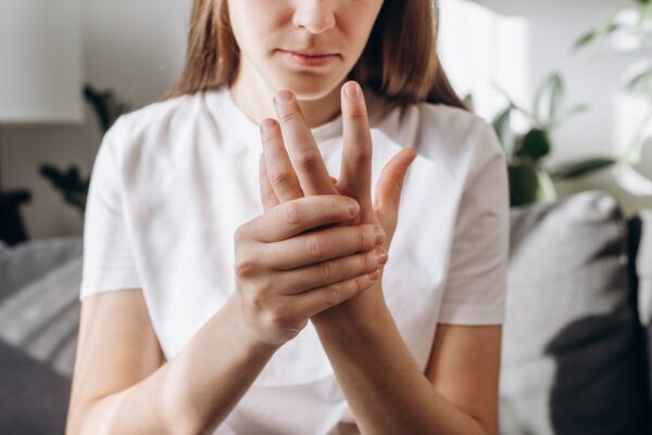 Fotografi av kvinne som tar seg til hånda, symptomer på revmatisk sykdom