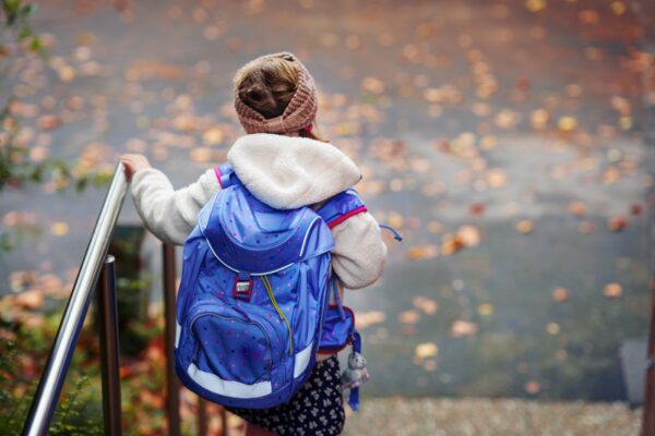 Fotografi av barn på vei til skolen, med ryggsekken på i høstvær