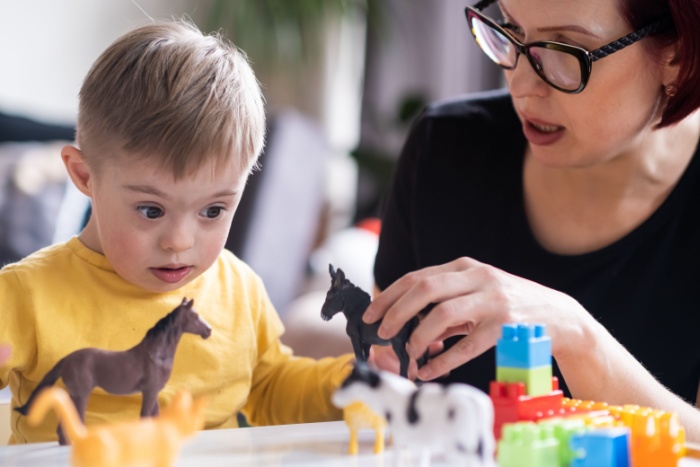 Barn med Downs syndrom i lek med en voksen